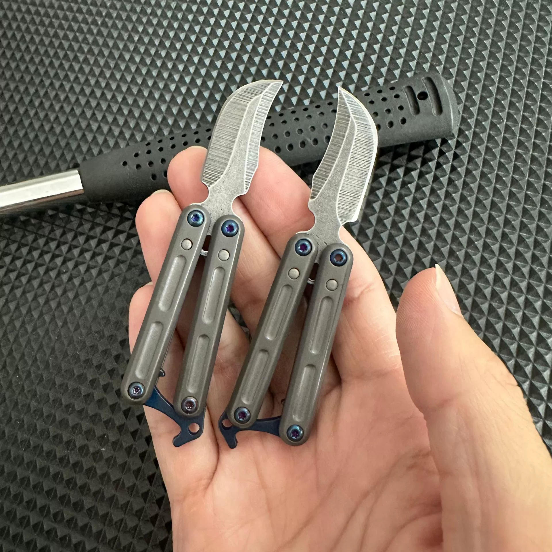 Two mini stainless steel butterfly knives shown open and folded
